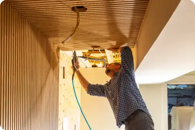 A man nailing decorative trim to the ceiling