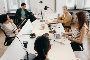 Media employees seated around a table working and talking